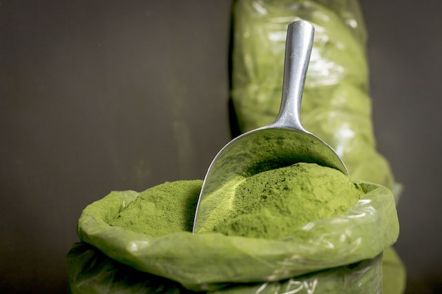 a sack of kratom powder and a stainless retail spoon